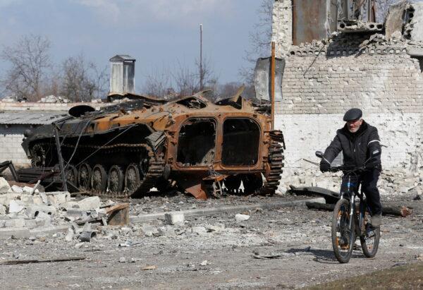 A local resident rides a bicycle past a charred armored vehicle during the Ukraine-Russia conflict in the separatist-controlled town of Volnovakha in the Donetsk region, Ukraine, on March 15, 2022. (Alexander Ermochenko/Reuters)