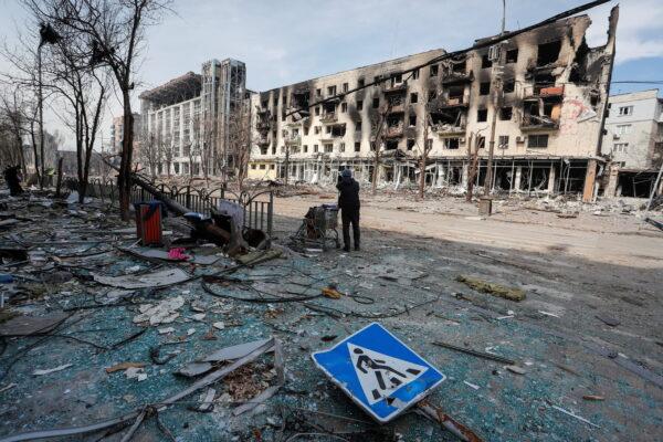 A resident stands with her belongings on a street near a building burnt in the course of the Ukraine-Russia conflict, in the southern port city of Mariupol, Ukraine, on April 10, 2022. (Alexander Ermochenko/Reuters)