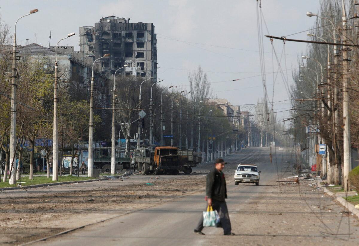 A resident crosses a street damaged during the Ukraine-Russia conflict in the southern port city of Mariupol, Ukraine, on April 15, 2022. (Alexander Ermochenko/Reuters)