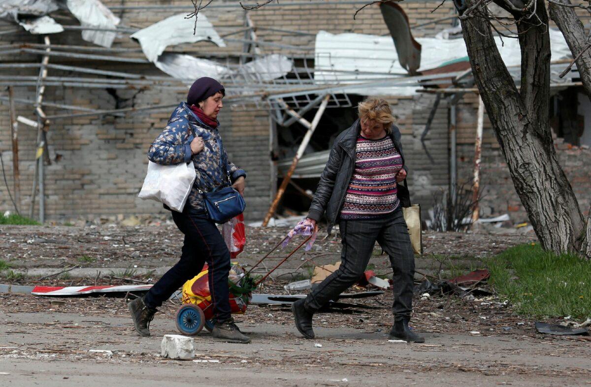 Women walk past a building damaged during the Ukraine-Russia conflict in Mariupol, Ukraine, on April 21, 2022. (Alexander Ermochenko/Reuters)