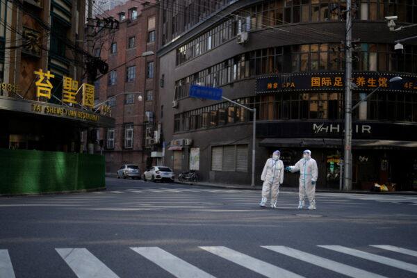 Workers in protective suits keep watch on a street during a lockdown amid the COVID-19 pandemic, in Shanghai, on April 16, 2022. (Aly Song/Reuters)