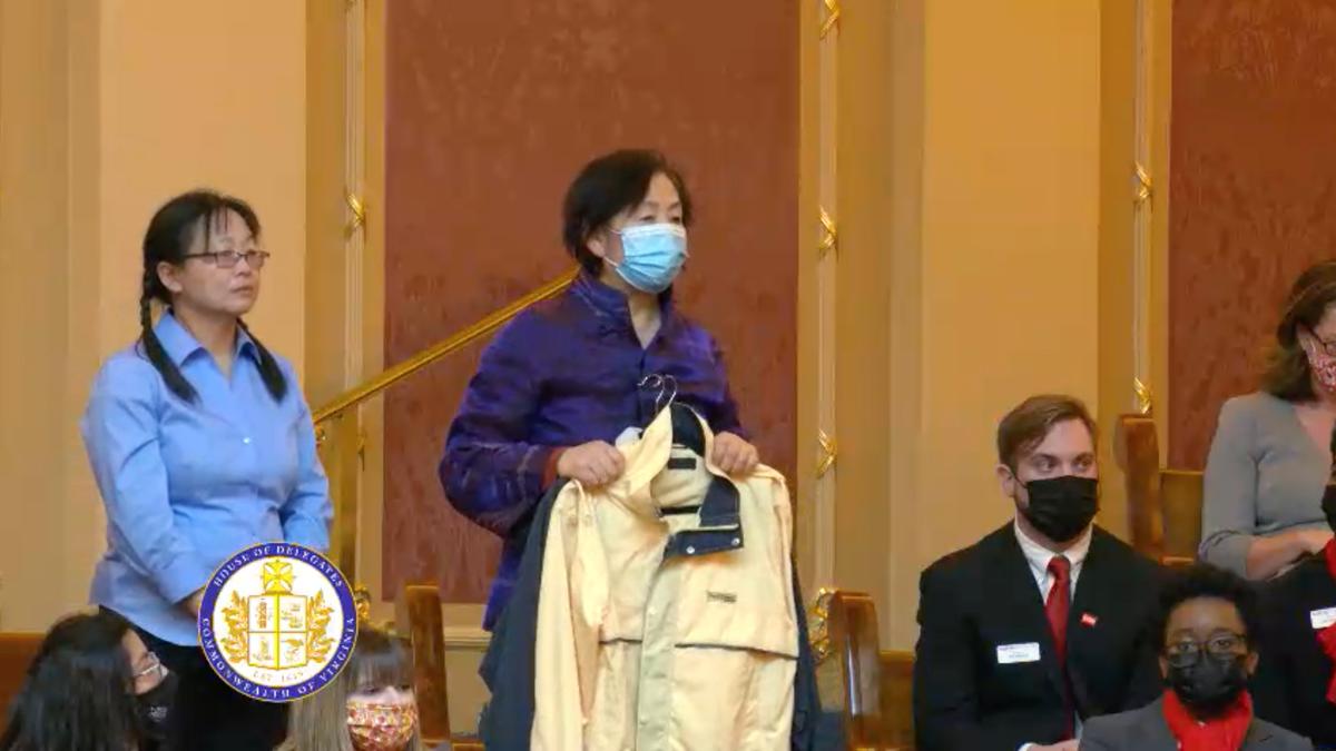 Wang Chunyan (C) holds the slave labor jacket she smuggled from Liaoning Women's Prison in northeast China as Del. Kaye Kory introduces her to members of the Virginia General Assembly during the regular session in Richmond, Va., on Jan. 25, 2022. (Screenshot of Virginia General Assembly Livestream via The Epoch Times)