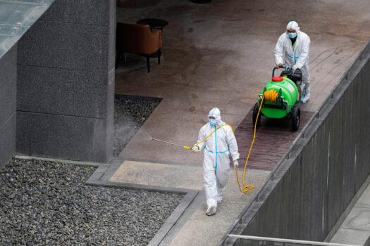 Workers in protective suits spray disinfectant around a community during the lockdown in Shanghai on April 5, 2022.(Aly Song/Reuters)