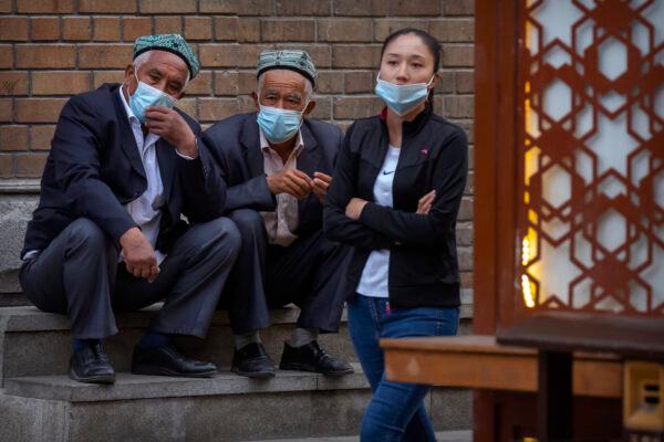 Uyghur men sit on steps in Urumqi in western China's Xinjiang Uyghur Autonomous Region, April 21, 2021. (AP/Mark Schiefelbein)