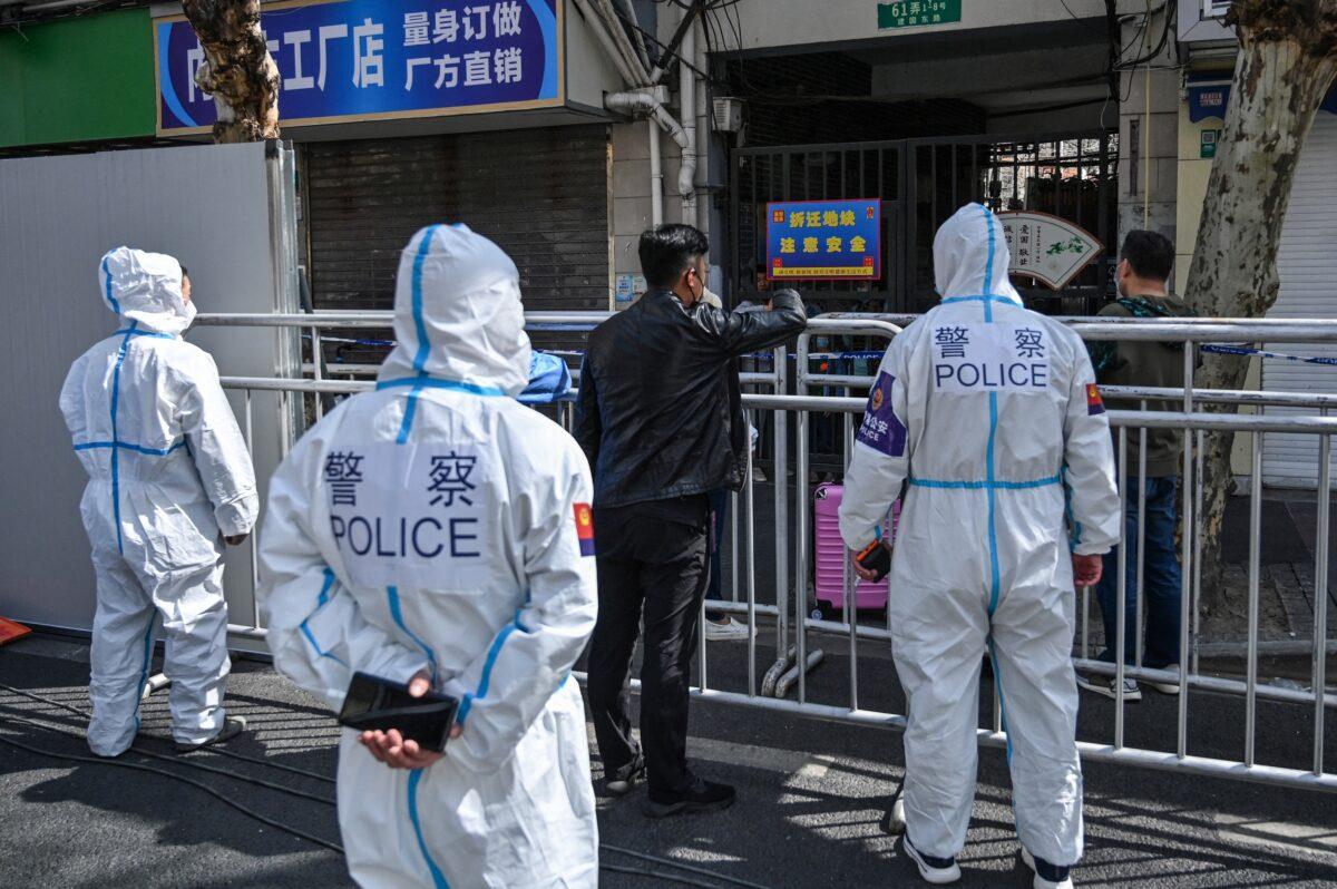 Police and officials wearing protective gear work in an area where barriers are being placed to close off streets around a locked-down neighborhood in Shanghai on March 15, 2022. (Hector Retamal/AFP via Getty Images)