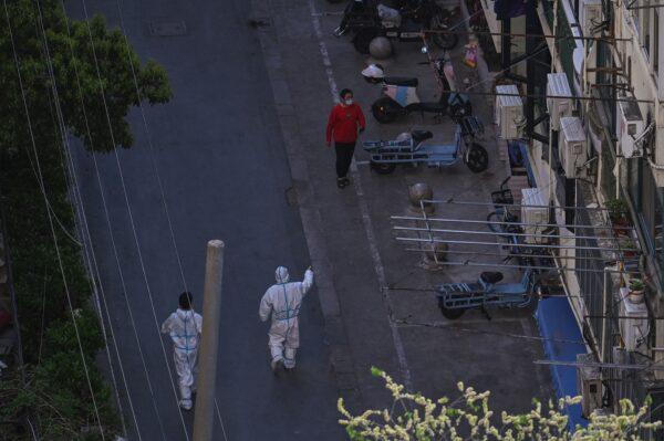 A worker wearing personal protective equipment (PPE) talks to a resident on a street during a COVID-19 lockdown in the Jing'an district in Shanghai on April 9, 2022. (Hector Retamal/AFP via Getty Images)