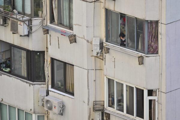  A woman looks out an apartment window during a COVID-19 lockdown in the Jing'an district in Shanghai on April 9, 2022. (Hector Retamal/AFP via Getty Images)