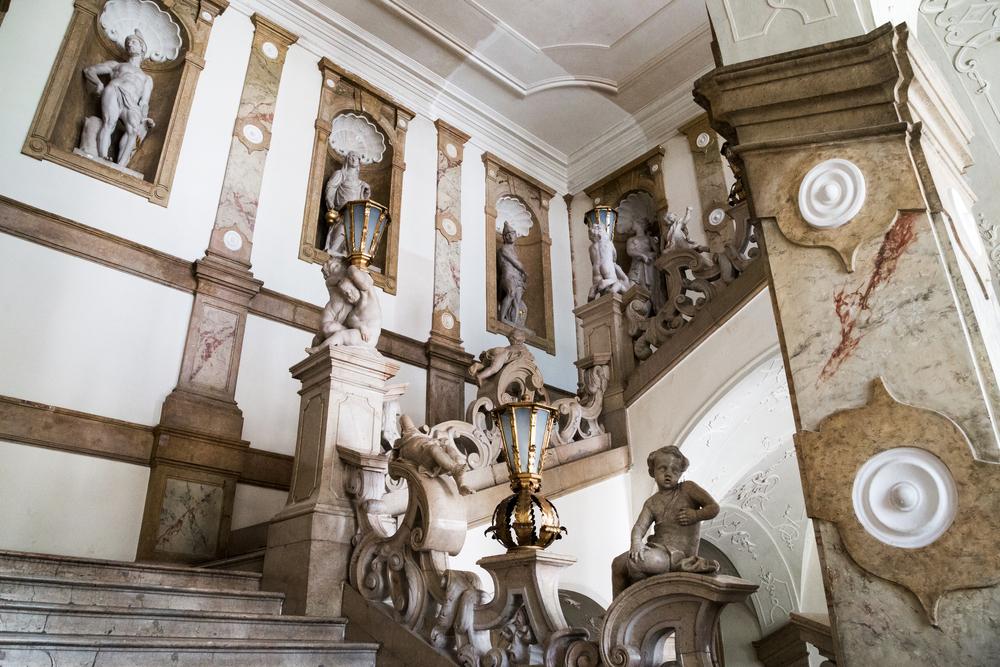  In order to attend a concert in the Marble Hall, visitors must first climb the “Donnerstiege” (or “Staircase of Thunder”) named after Georg Raphael Donner who sculpted its marvelous statues. Another Baroque masterpiece, the staircase is decorated with cherubs, mythological figures, marble columns, and a one-of-a-kind rococo, sculptural banister. White roundels or “bullseye” circular moldings stand out against the marble columns perhaps with intentional, spiritual symbolism. (goga18128/Shutterstock)