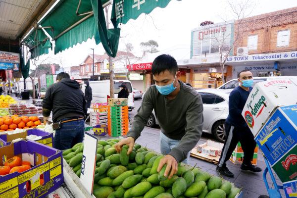 Workers wear face masks as they set up displays at a local fruit and vegetable market in Sydney, Australia, on July 9, 2021. (Lisa Maree Williams/Getty Images)