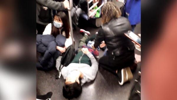 People tend to a bloodied passenger lying on the subway floor after a shooting at the 36th Street station in Brooklyn, New York, on April 12, 2022. (Epoch Times staff)
