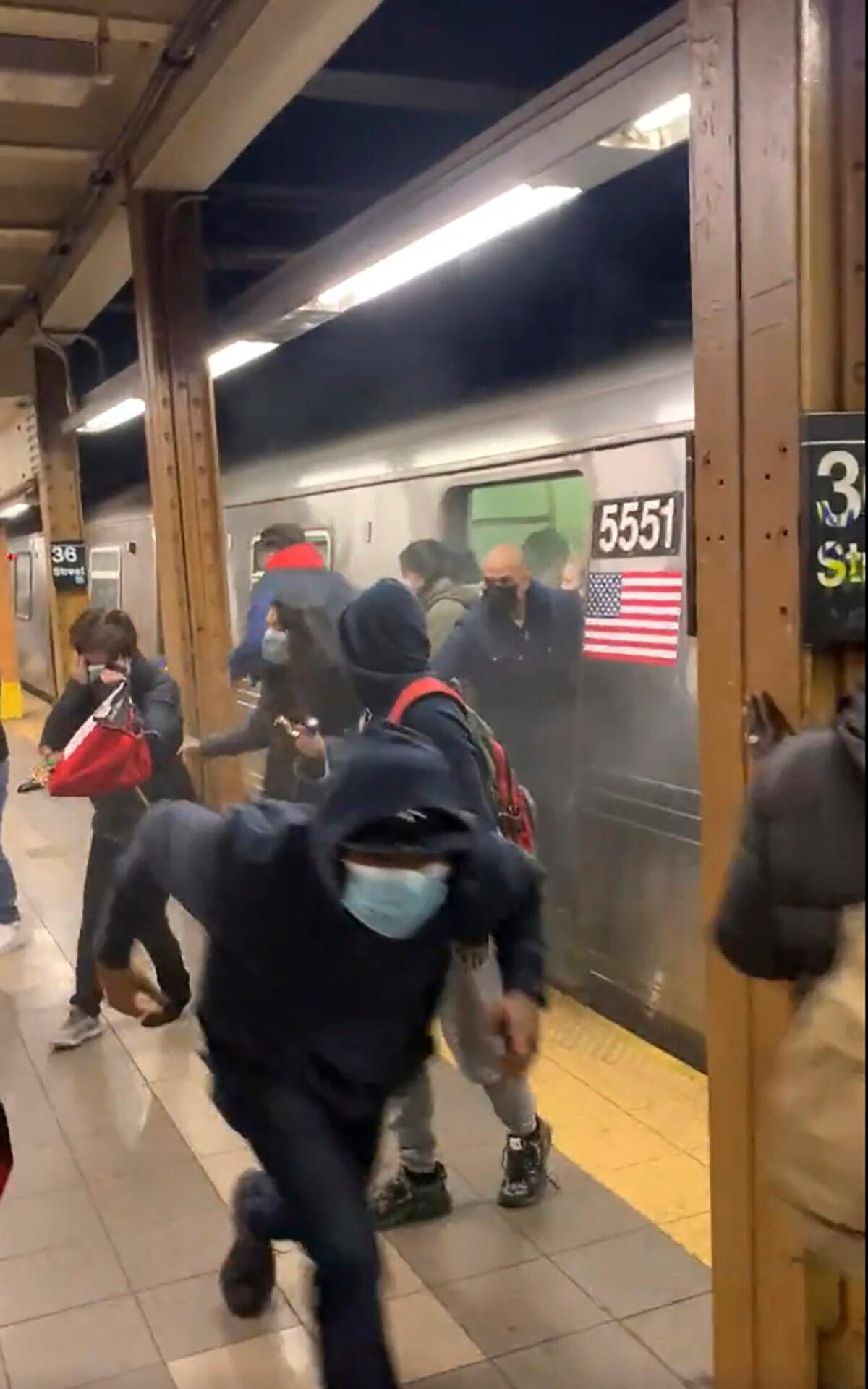 In this photo from social media video, passengers run from a subway car in a station in the Brooklyn borough of New York on April 12, 2022. (Will B. Wylde via AP)