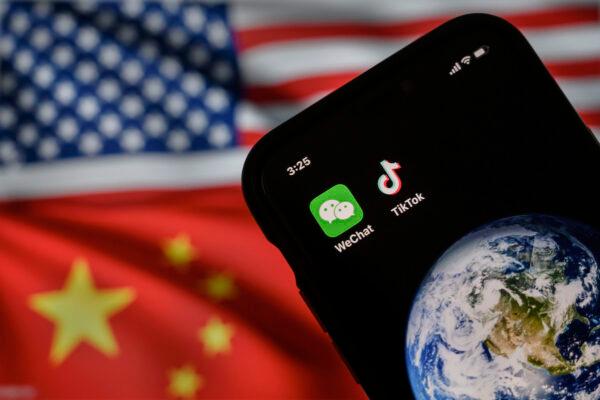 In this photo illustration, a mobile phone can be seen displaying the logos for Chinese apps WeChat and TikTok in front of a monitor showing the flags of the United States and China on an internet page, on Sept.22, 2020, in Beijing, China. (Kevin Frayer/Getty Images)