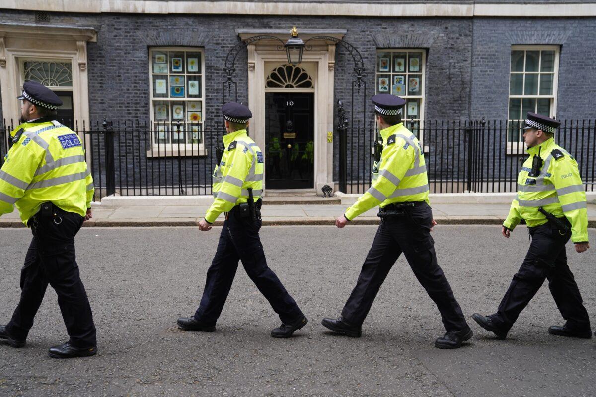 During a protest outside the gates, a group of police officers walk through Downing Street, in London, on April 13, 2022. (Stefan Rousseau/PA)
