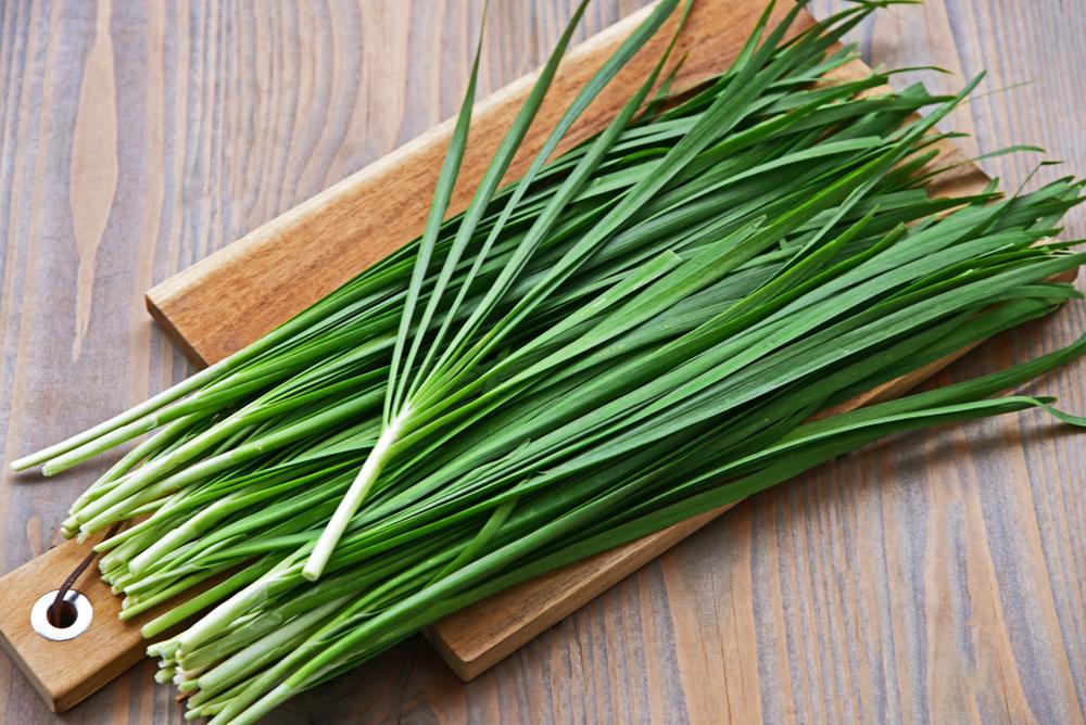 Garlic chives are less onion-y than regular chives or scallions, and have more garlic pungency. (PosiNote/Shutterstock)