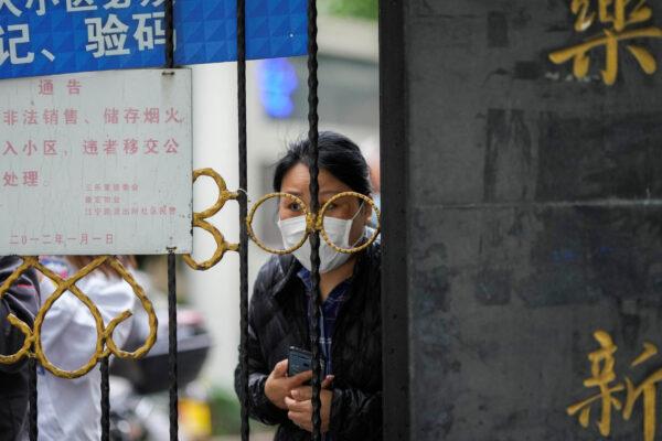 A resident looks out behind a gate blocking an entrance to a residential area under lockdown in Shanghai, China, on April 13, 2022. (Aly Song/Reuters)