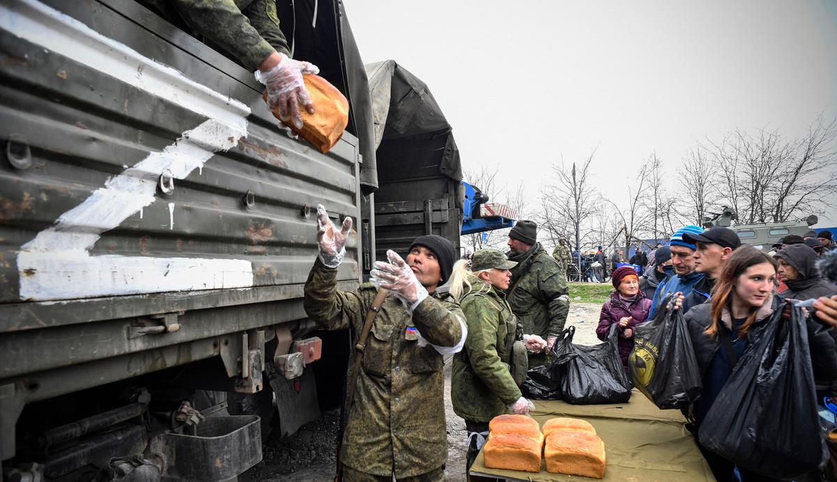  Russian soldiers and volunteers distribute bread in Mariupol on April 12, 2022, as Russian troops intensify a campaign to take the strategic port city, part of an anticipated massive onslaught across eastern Ukraine, while Russia's president makes a defiant case for the war on Russia's neighbor. - *EDITOR'S NOTE: This picture was taken during a trip organized by the Russian military.* (Alexander Nemenov/AFP via Getty Images)
