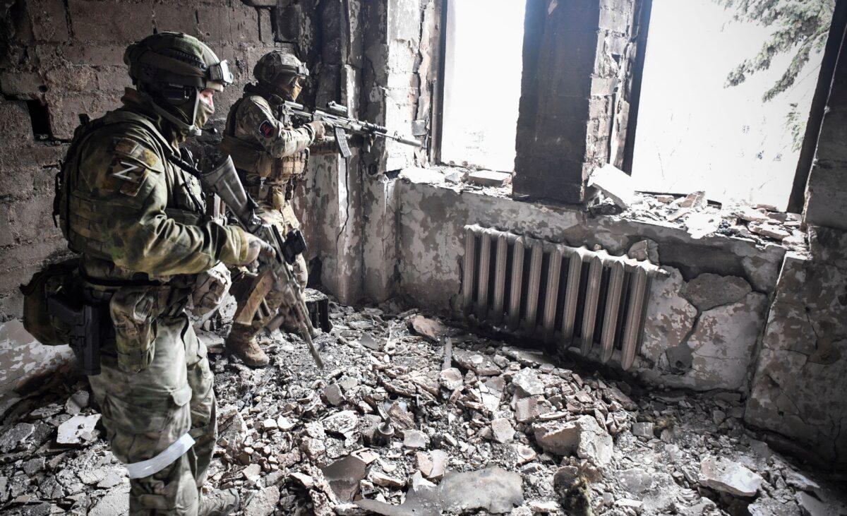 Two Russian soldiers patrol in the Mariupol drama theater, which was bombed on March 16, in Mariupol, Ukraine, on April 12, 2022. (Alexander Nemenov/AFP via Getty Images)