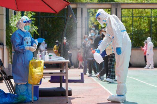 A community volunteer wearing personal protective equipment disinfects an area before conducting a test for the COVID-19 coronavirus in a compound during a pandemic lockdown in Pudong district in Shanghai on April 17, 2022. (Liu Jin/AFP via Getty Images)