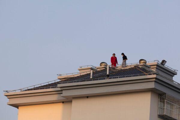 People stand on a rooftop at a residential community in Shanghai on April 11, 2022. (AP Photo)