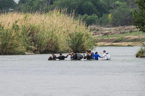A group of Cubans wade across the Rio Grande toward the United States from Mexico, in Eagle Pass, Texas, on April 19, 2022. (Charlotte Cuthbertson/The Epoch Times)