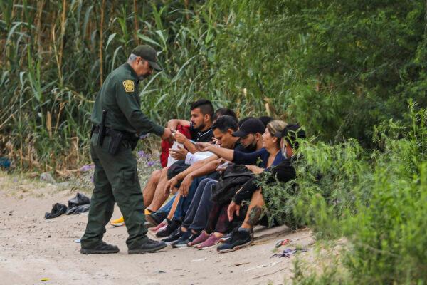 A Border Patrol agent apprehends a group of Cubans who just crossed the Rio Grande from Mexico into Eagle Pass, Texas, on April 19, 2022. (Charlotte Cuthbertson/The Epoch Times)