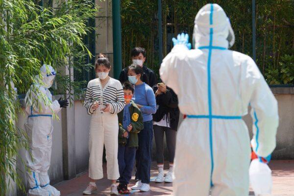  Community volunteers wearing personal protective equipment guide residents queuing to get tested for the COVID-19 during a lockdown in the Pudong district of Shanghai on April 17, 2022. (Liu Jin/AFP via Getty Images)
