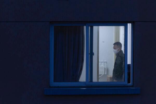 A man with a mask is seen through a window at his home in a residential area on April 13, 2022, in Shanghai, China. (Getty Images/Getty Images)