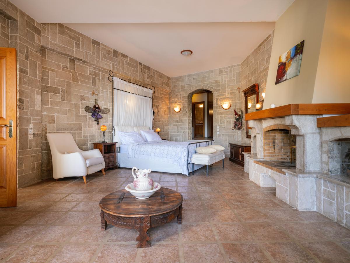 Fabulous stonework, attention to detail, and uncompromising craftsmanship resonate throughout the residences. Here the master suite features a massive fireplace. (Courtesy of Greece Sotheby's International Realty)
