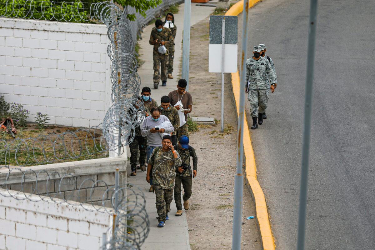 A group of Mexicans walks back into Mexico after being returned halfway along the international bridge from the United States under Title 42, in Piedras Negras, Mexico, on April 21, 2022. (Charlotte Cuthbertson/The Epoch Times)