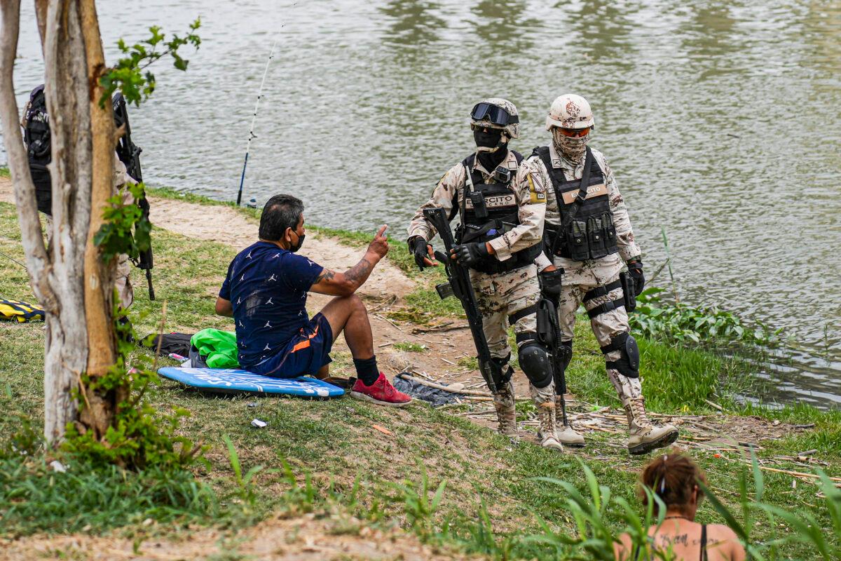 Mexican federal military troops check the identification of people on the bank of the Rio Grande across from the United States, in Piedras Negras Mexico, on April 21, 2022. (Charlotte Cuthbertson/The Epoch Times)
