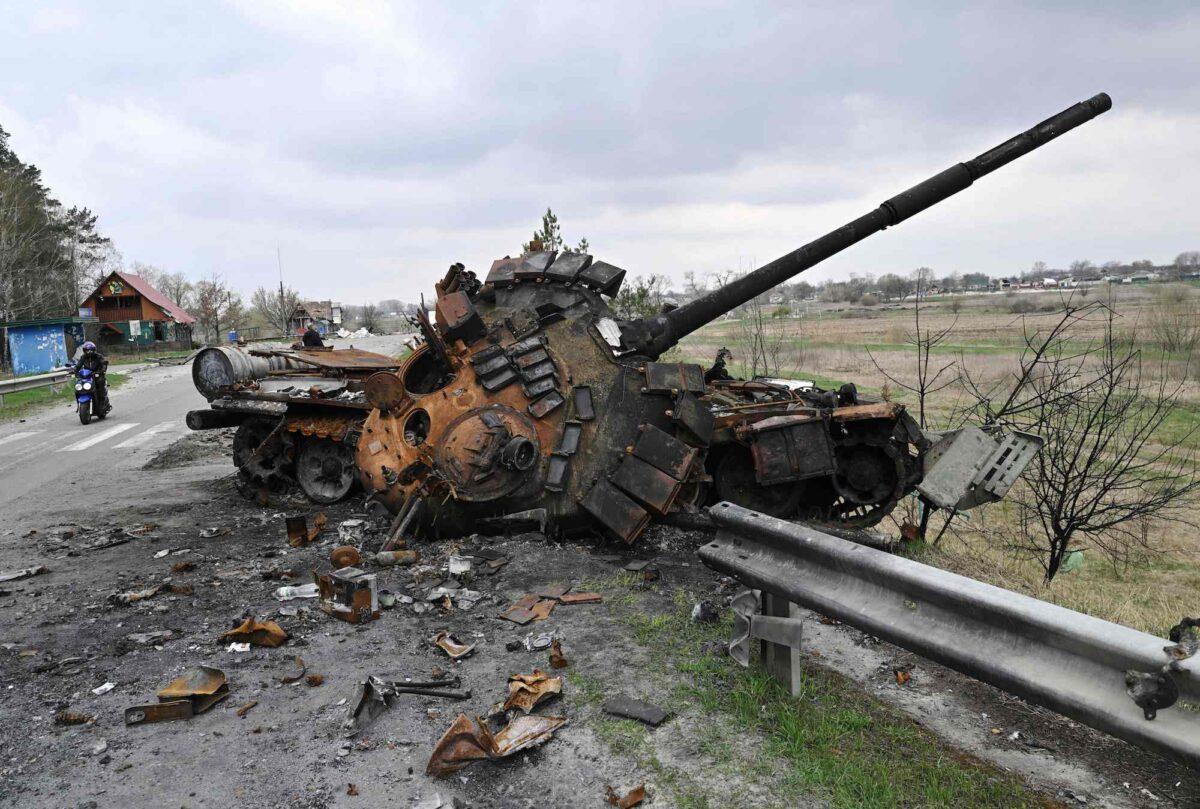 A man rides a motorbike past a destroyed Russian tank on a road in the village of Rusaniv, near Kyiv, Ukraine, on April 16, 2022. (Genya Savilov/AFP/Getty Images)