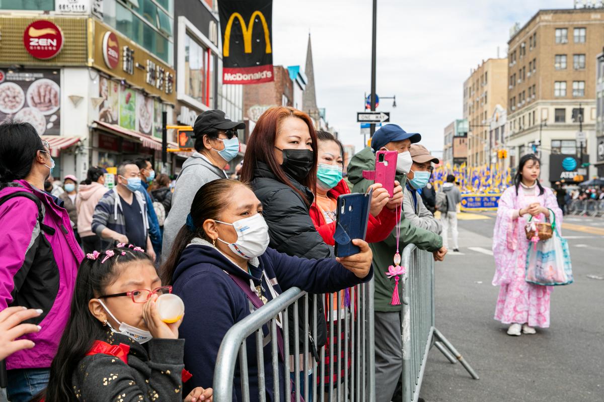 Bystanders join Falun Gong practitioners in a parade to commemorate the 23rd anniversary of the April 25th peaceful appeal of 10,000 Falun Gong practitioners in Beijing, in Flushing, N.Y., on April 23, 2022. (Chung I Ho/The Epoch Times)