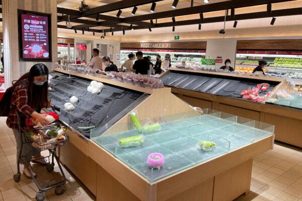 Customers shop next to near-empty shelves at a supermarket in Chaoyang district of Beijing, on April 24, 2022.(Stella Qiu/Reuters)