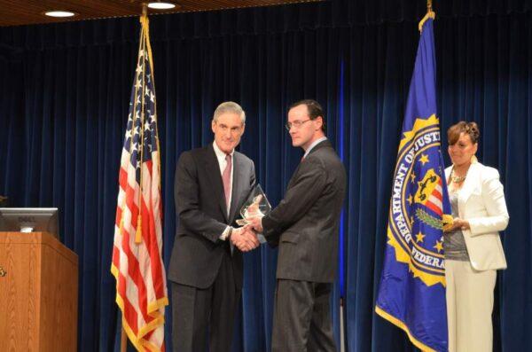 Then-FBI Director Robert Mueller presents Tiversa founder Robert Boback with an award in 2013. (FBI/Screenshot by Epoch Times)