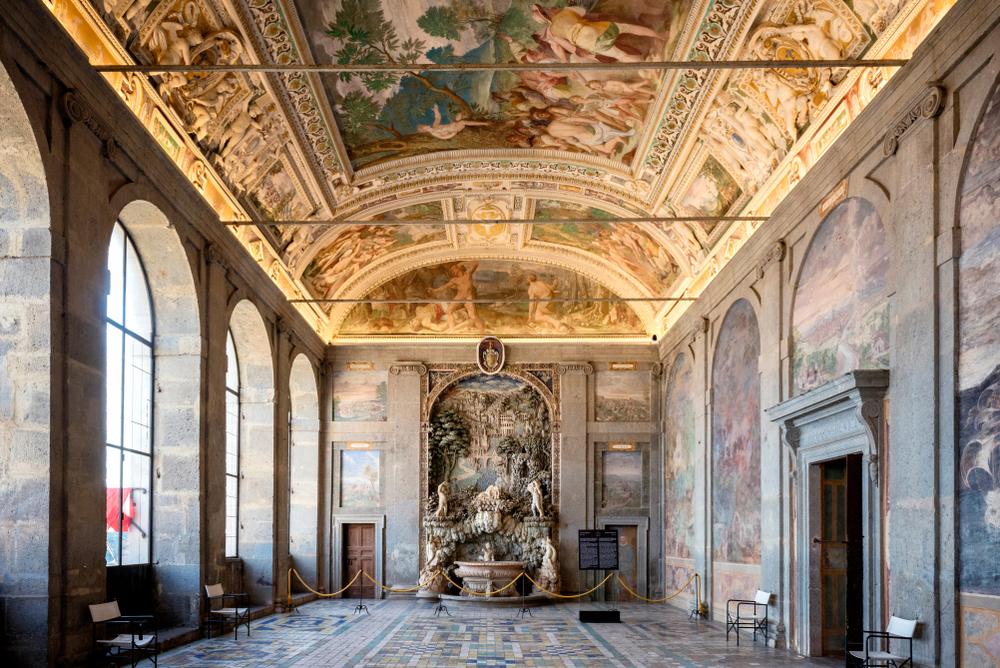 The large dining hall, known as the Room of Hercules, is detailed with frescoes depicting a legend of Hercules inadvertently creating the nearby lake of Vico. At the end of the room is a fountain grotto surrounded with cherubs and by a mosaic townscape. The sound of water once soothingly echoed through the room. (Massimo Santi/Shutterstock)