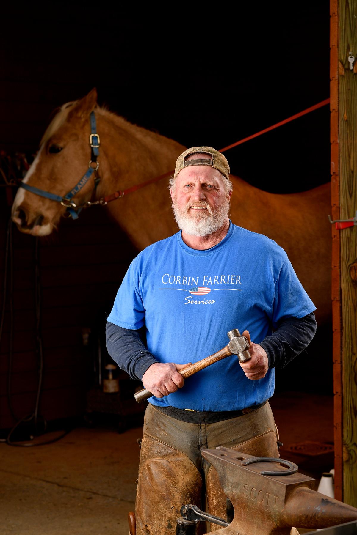 Terry Corbin of Corbin Farrier Services poses for a portrait while changing the horseshoes on Gambler's Golden Flame, a horse owned by Susan Smith, in Rixeyville, Va. (Randy Litzinger for The Epoch Times)
