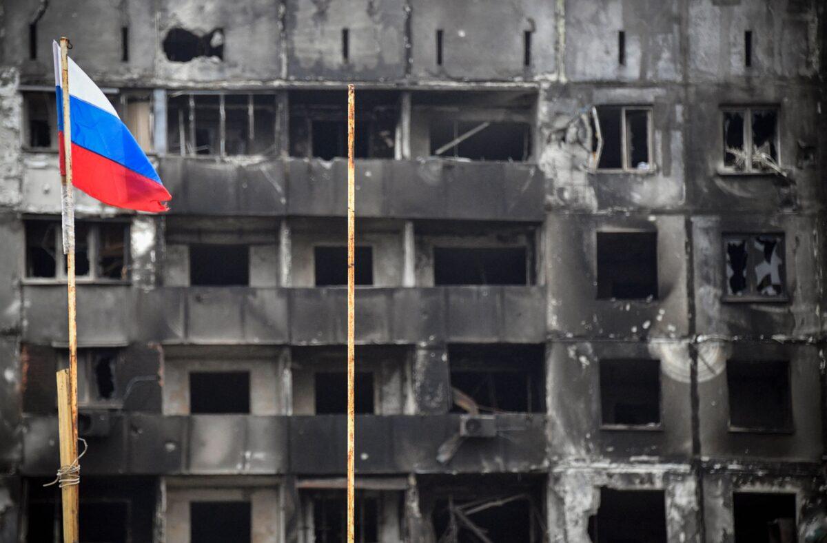 A Russian national flag flies by destroyed buildings in Mariupol, Ukraine, on April 12, 2022. (Alexander Nemenov/AFP via Getty Images)
