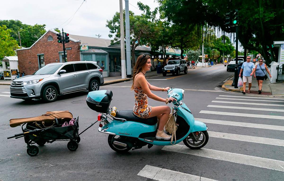 Singer Elle Haley rides a scooter with her music equipment as she makes her way toward Hank’s Hair of the Dog Saloon in Key West, Florida, on Dec. 12, 2021. (Matias J. Ocner/Miami Herald/TNS)
