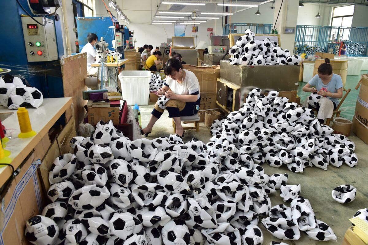 Workers make football overtime to process additional football orders from Russian, Brazilian, and other overseas customers at the producing department of Aokai Sports Goods Co., Ltd. on July 5, 2018, in Yiwu, Zhejiang Province of China. (VCG)