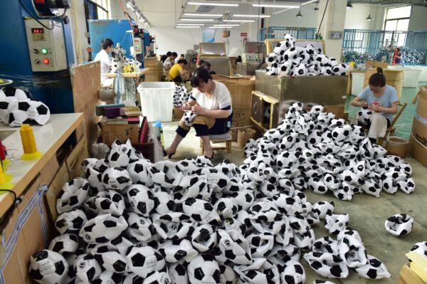 Workers make soccer balls overtime to process additional orders from Russian, Brazilian, and other overseas customers at Aokai Sports Goods Co., Ltd., in Yiwu, Zhejiang Province of China, on July 5, 2018. (VCG/Stringer via Getty Images)