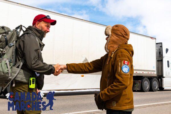 Former military member, Sunil Ram, greets James Topp (L) along his march route near Regina, Sask., on April 21, 2022. (Courtesy Logan Murphy)