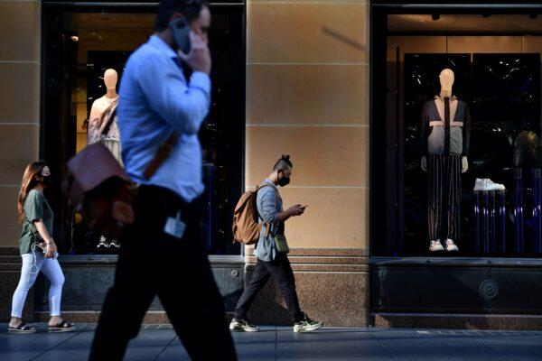 People walk past a retail store in Sydney, Australia, on March 19, 2020. (Saeed Khan/AFP via Getty Images)