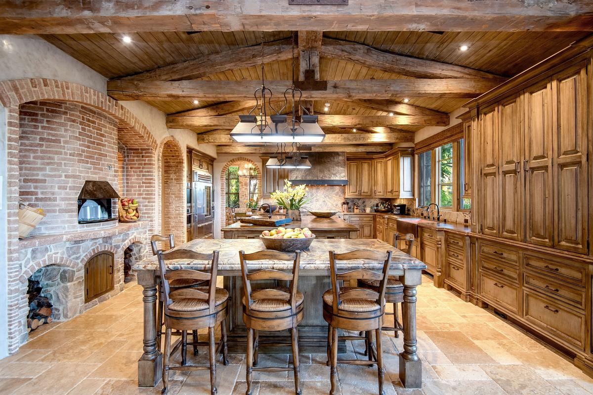 The home’s magnificent kitchen with a custom wood-fired pizza oven, double islands, and flawlessly crafted stone and woodwork. There’s a cozy breakfast nook adjacent and professional quality appliances throughout. (Jade Mills)