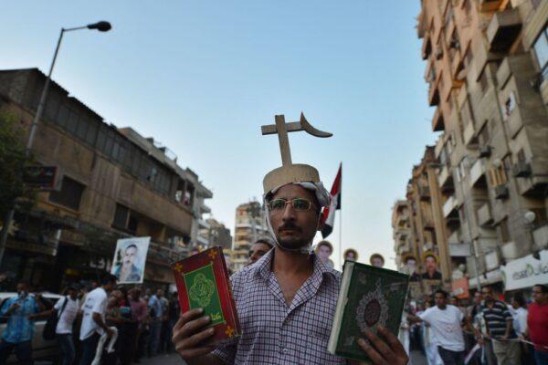 An Egyptian Coptic man holds a Bible and a Koran during a march in Cairo in Cairo on October 9, 2012 to mark one year since nearly 30 demonstrators were killed in a Coptic Christian demonstration that was violently crushed by security forces. (Khaled Desouki/AFP via Getty Images)