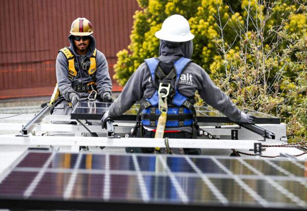 Luminalt solar installers Pam Quan (R) and Walter Morales install solar panels on the roof of a home in San Francisco on May 9, 2018. (Justin Sullivan/Getty Images)