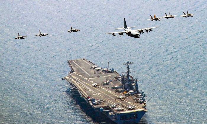 A U.S. Marine Corps C-130 Hercules aircraft leads a formation over the aircraft carrier USS George Washington off the coast of South Korea on July 27, 2010. (Mass Communication Specialist 3rd Class Charles Oki/U.S. Navy via Getty Images)