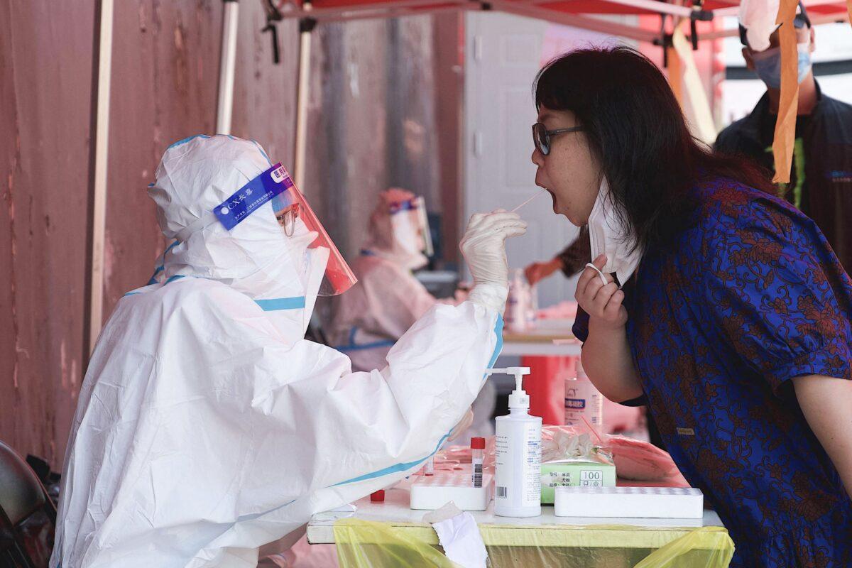 A health worker takes a swab sample from a woman, to be tested for the COVID-19 coronavirus, at a swab collection site in Beijing, China, on May 3, 2022. (Noel Celis/AFP via Getty Images)