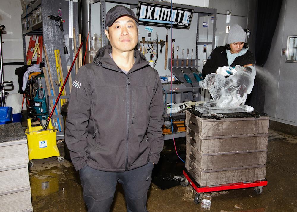 Shintaro Okamoto (L) stands in his ice sculpting studio, as Christian Lopez works on a piece for a client. (Dave Paone/The Epoch Times)