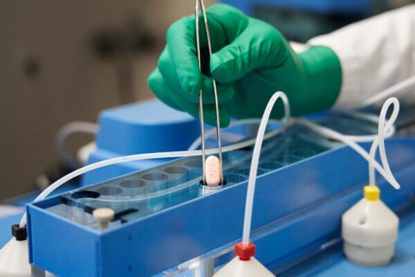 A Pfizer technician handles the company's COVID-19 pill, known as Paxlovid, in a file photograph. (Pfizer via AP)