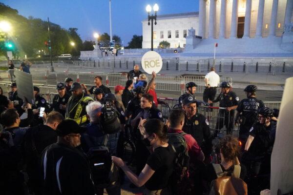 A.J. Hurley (rear left), Rev. Patrick Mahoney (rear left center), Pastor Mark Lee Dickson (rear right center), and Bryan Kemper (rear right), stand in front of the Supreme Court while surrounded by police and protesters on May 4, 2022. (Jackson Elliott/The Epoch Times)